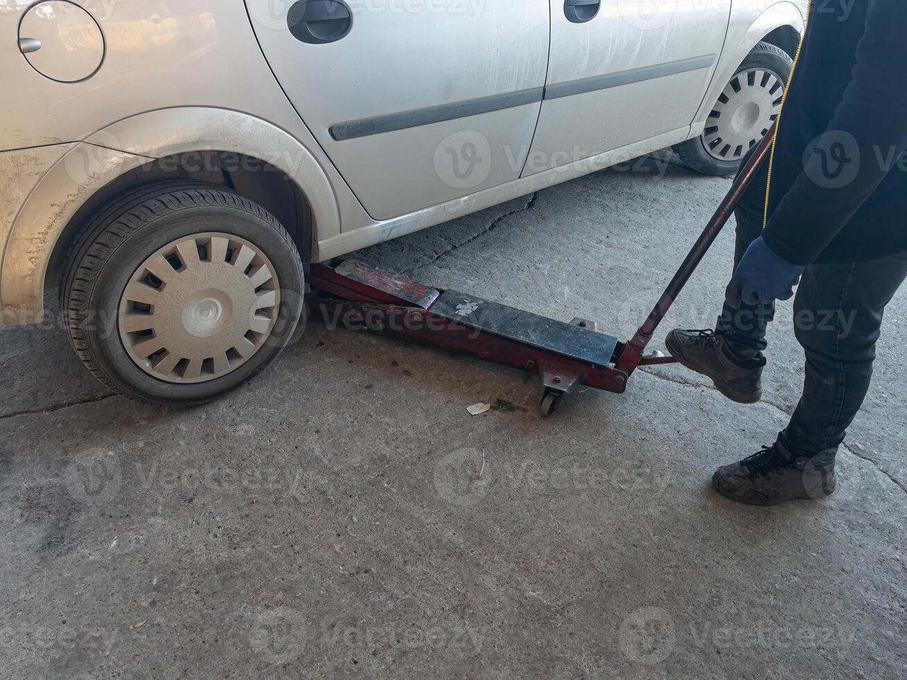 A mechanic using a jack to change a tyre on a car. photo