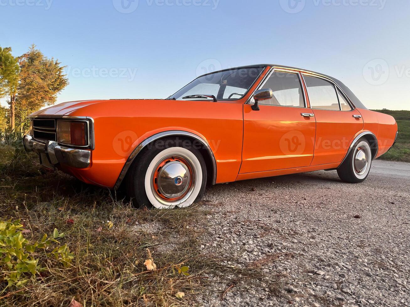 Orange classic car with a flat tire. photo