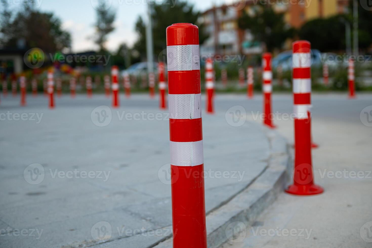 Orange traffic cone, parking is prohibited. Plastic red barrier. Row of red and white traffic barrier pole on road. A barrier made of plastic columns with reflective pigment on an asphalt road. photo