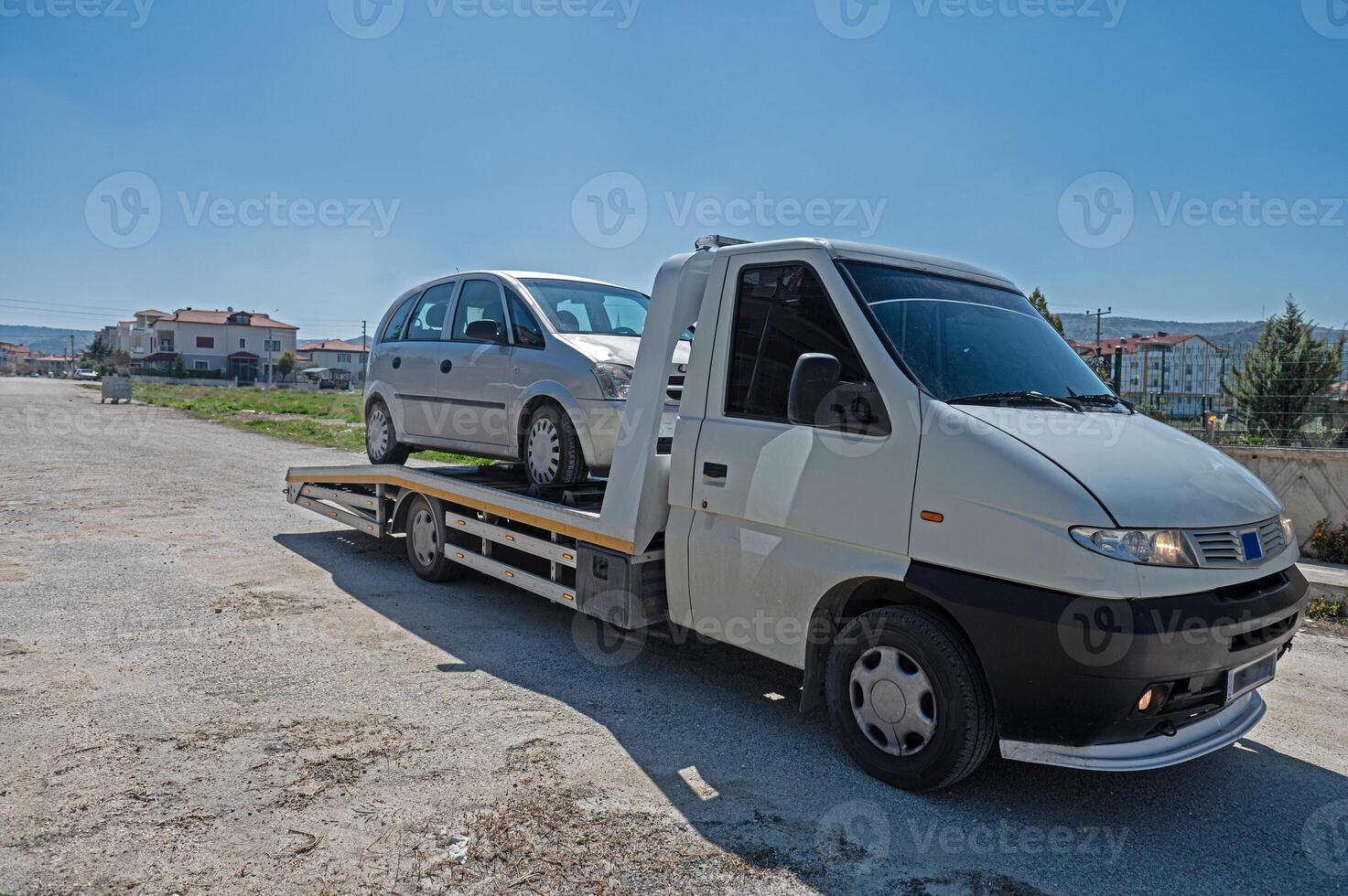 A man loading a broken down car onto a tow truck. Roadside assistance concept. photo