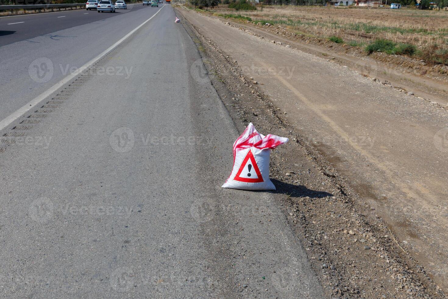 Warning sign indicating road work alongside a busy highway in a rural area photo