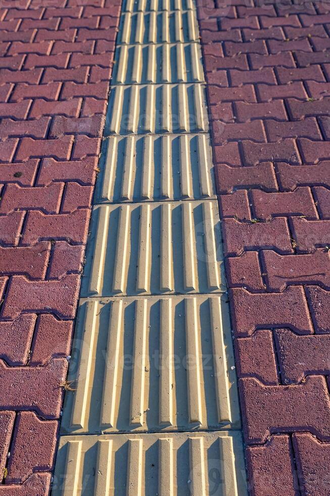 Tactile pavement for the disabled and blind, texture on tiles for the disabled, selective focus, pedestrian path. photo