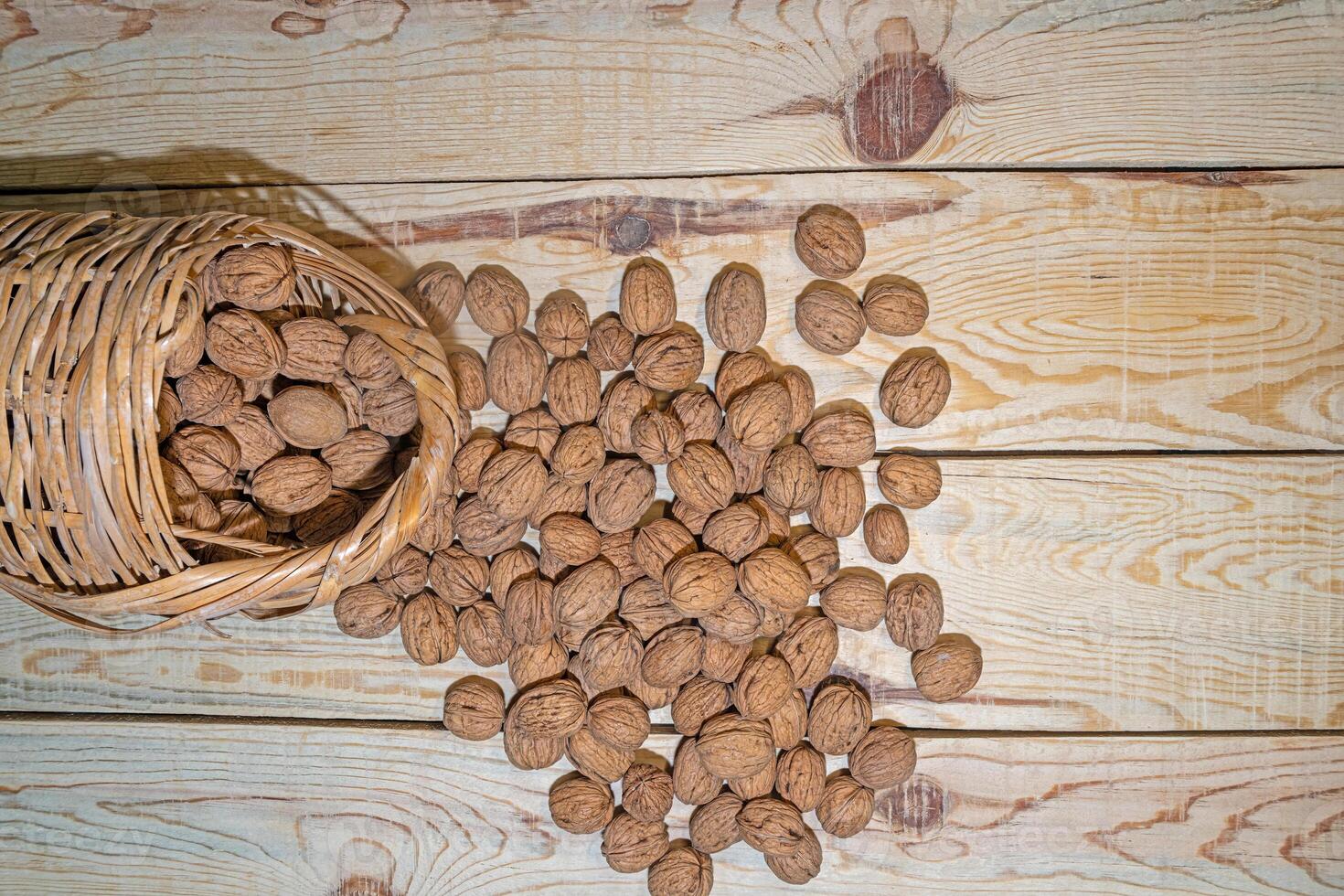 Poured walnuts in a wicker basket on a wooden table. View from above. photo