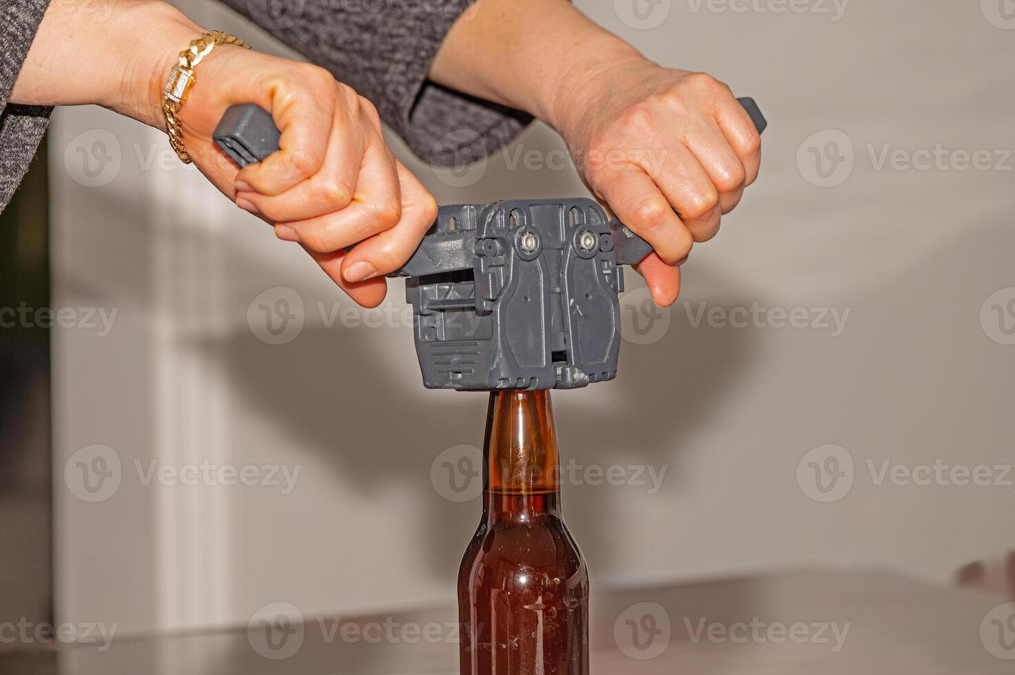 Woman using a cap to attach metal lids to beer bottles. photo