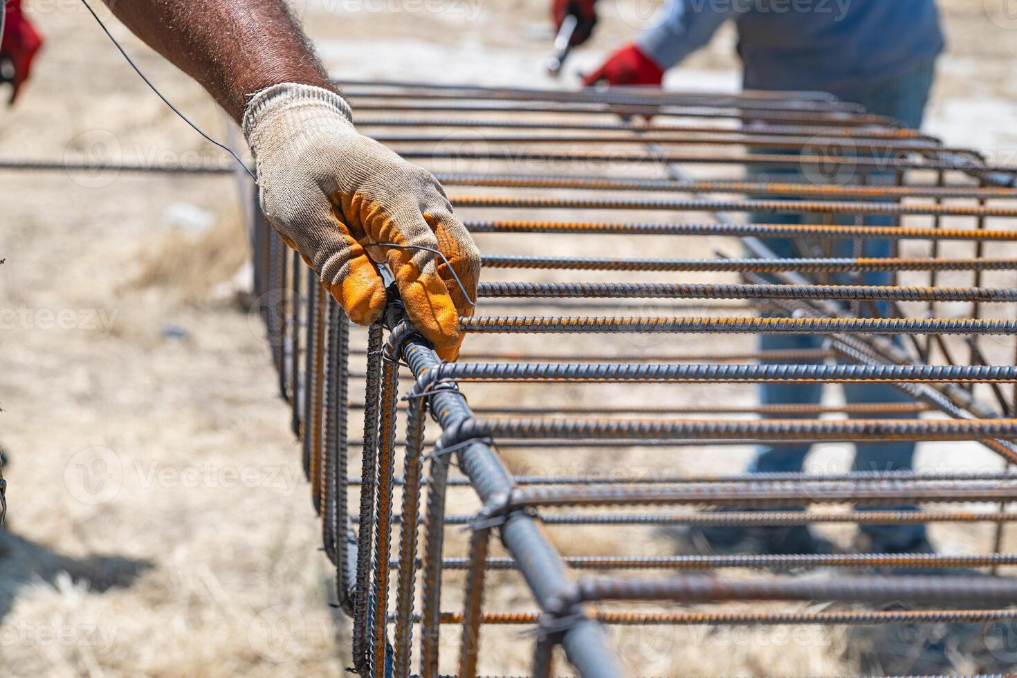 Workers use steel lacing wire to attach steel bars to reinforcing bars. Close-up. Reinforced concrete structures - knitting a metal reinforcing cage photo