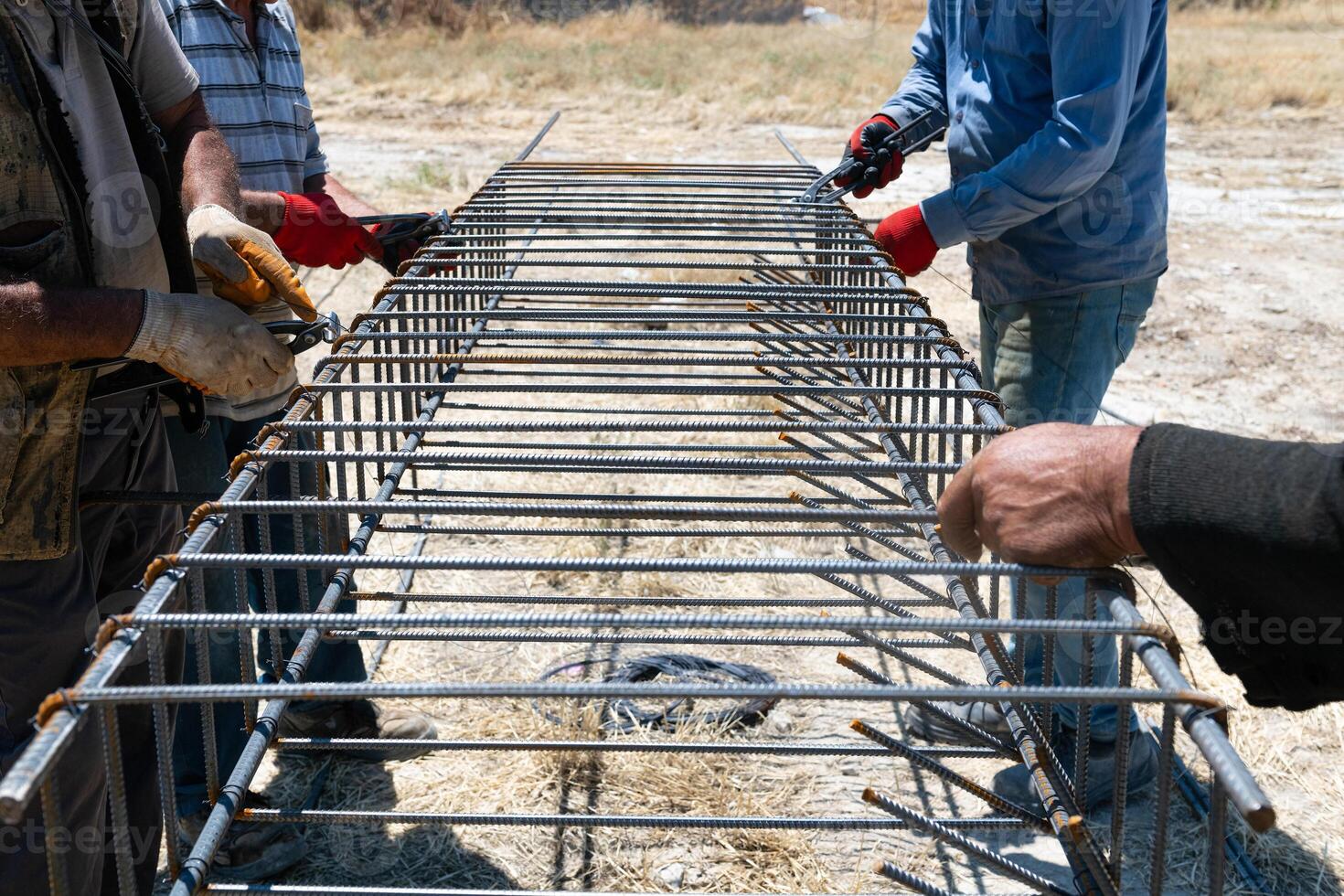 Workers use steel lacing wire to attach steel bars to reinforcing bars. Close-up. Reinforced concrete structures - knitting a metal reinforcing cage photo