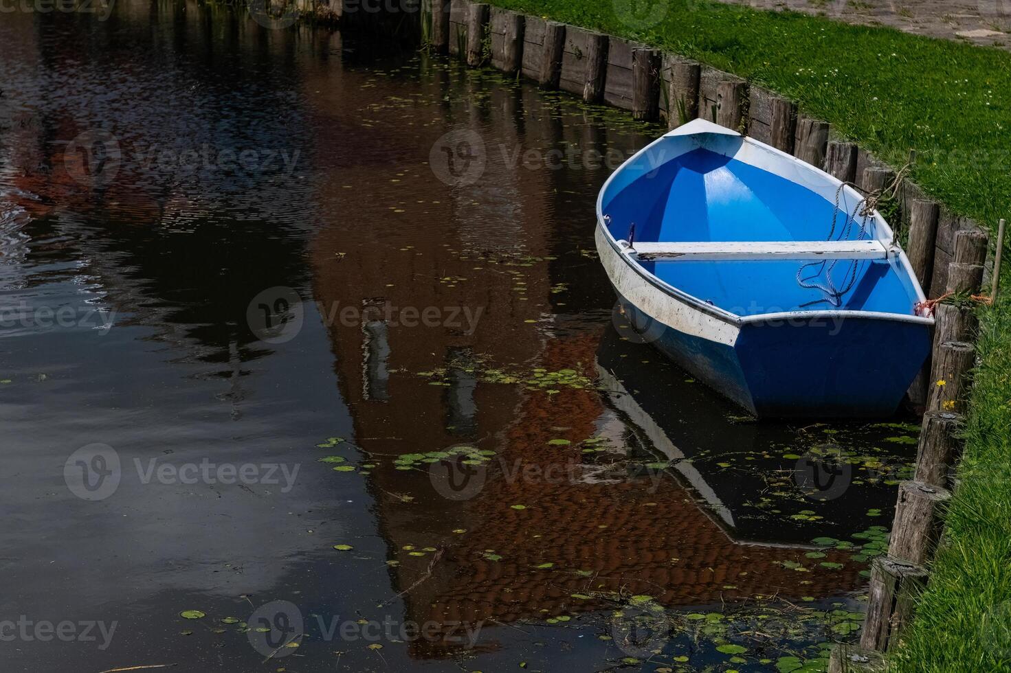 Empty and blue coloured boat moored by the pond. photo
