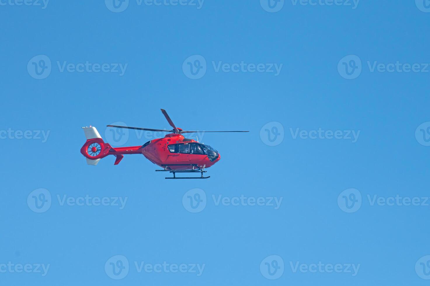 Red coloured helicopter flying in the sky. photo
