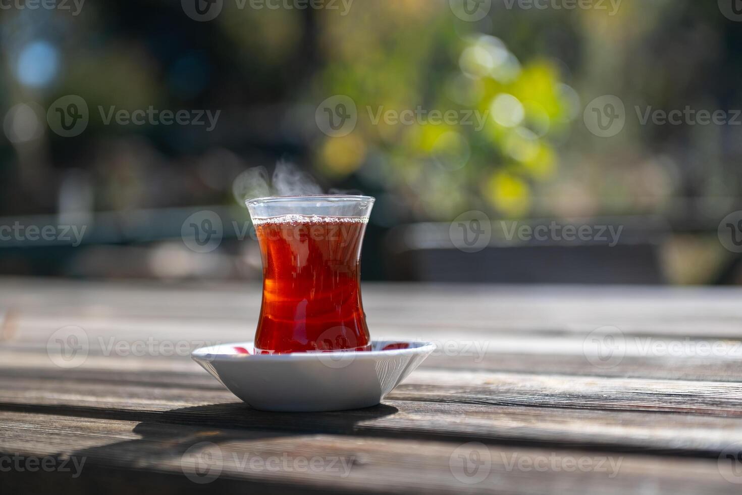 Hot Turkish tea in a glass cup on a wooden table. photo