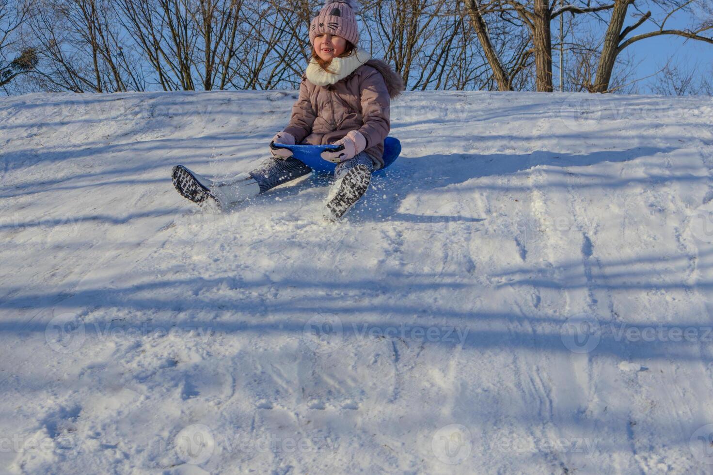 Child enjoying a snowy sledding adventure on a bright winter afternoon photo