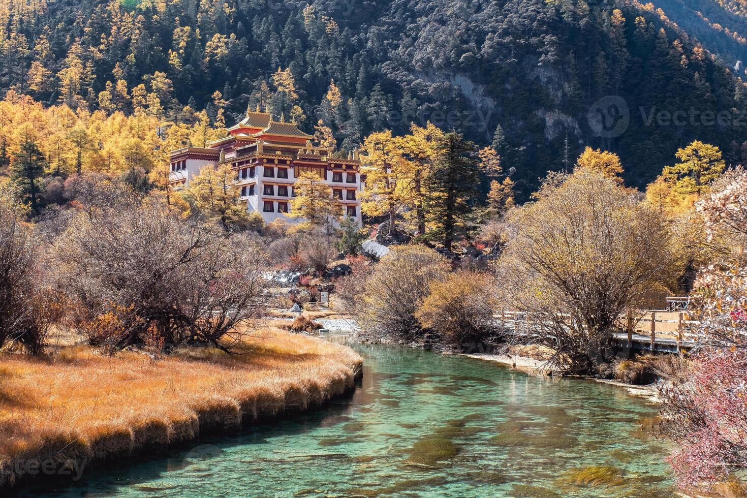 Chong Gu temple on autumn hill with emerald river at Yading photo