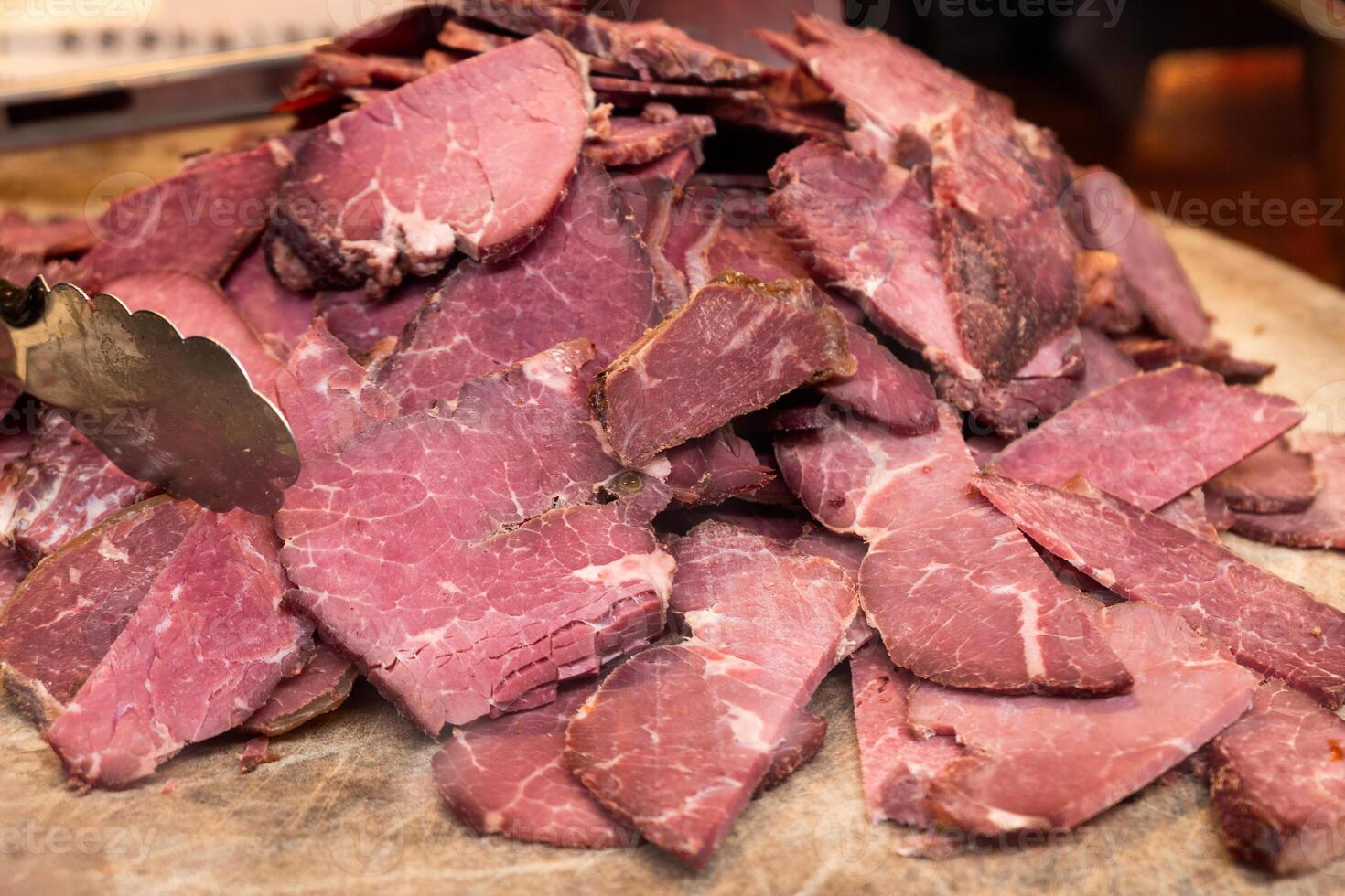 Sliced beef stacked on wooden chopping board photo