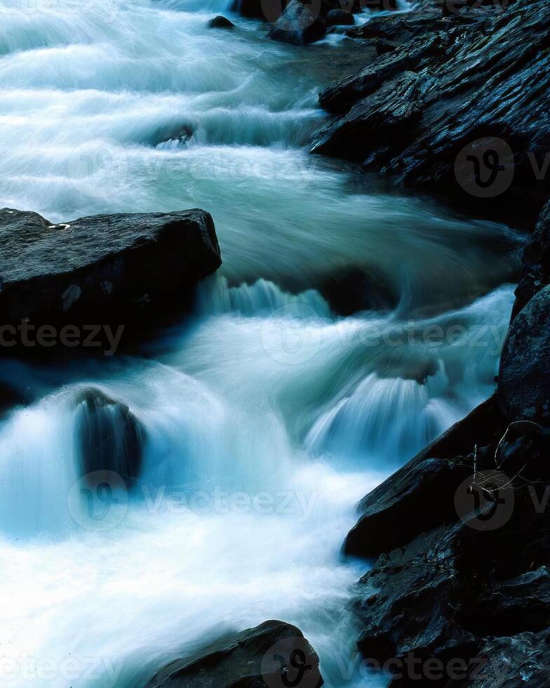 Majestic Mountain River Cascading Through Scenic Fluvial Landforms under a Bright Sky photo