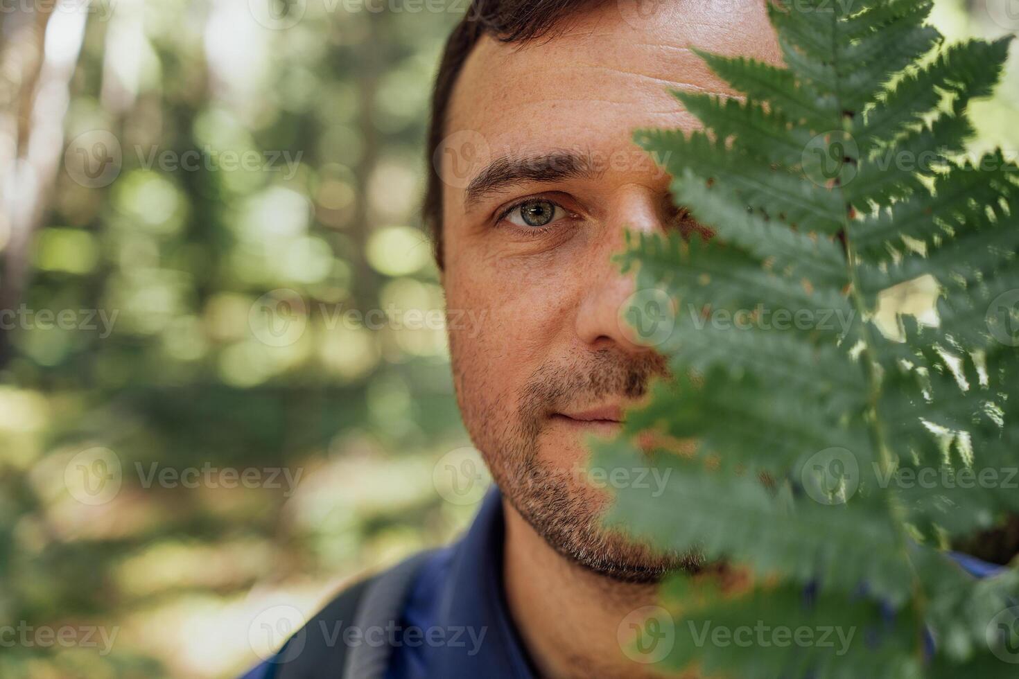 Close-up portrait of young happy man with fern in nature. photo