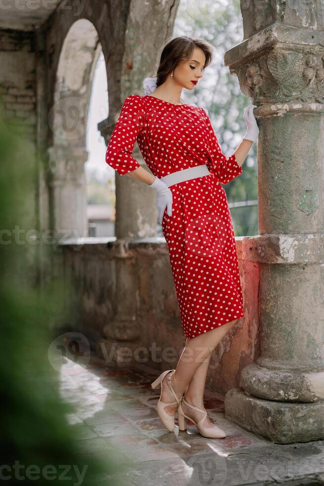 Elegant woman posing in red polka dot dress and white gloves photo