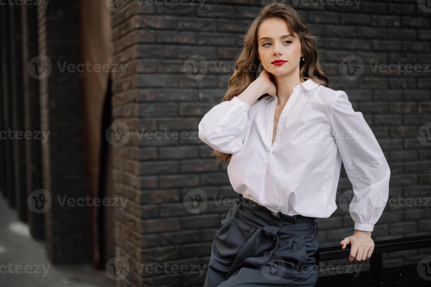 Elegant businesswoman posing near brick wall in urban setting photo