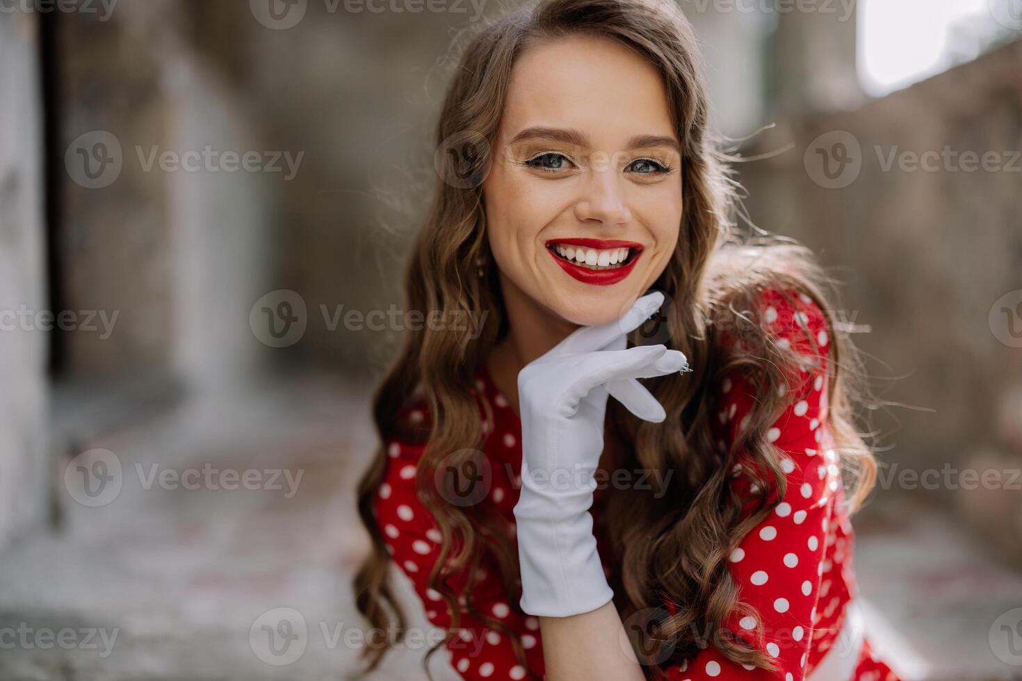 Smiling pin up girl wearing white gloves and red polka dot dress posing photo