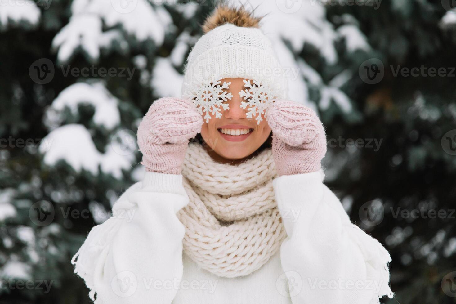 Happy woman in white winter clothes holding a beautiful snowflake in a park. Happy winter concept photo
