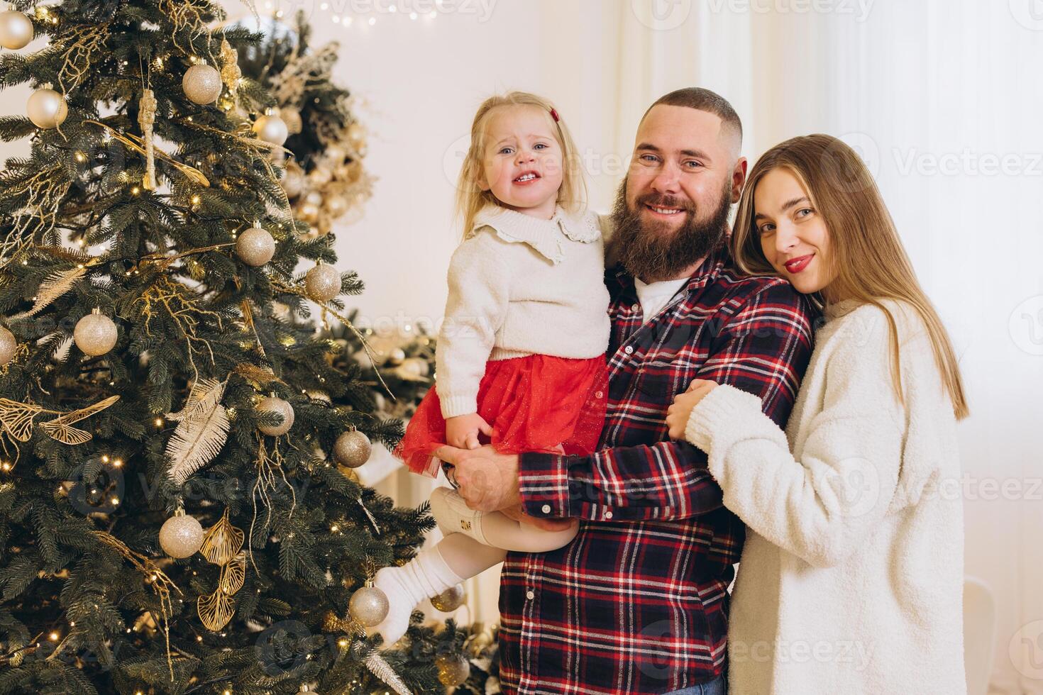 Happy family celebrating christmas at home by the decorated tree photo