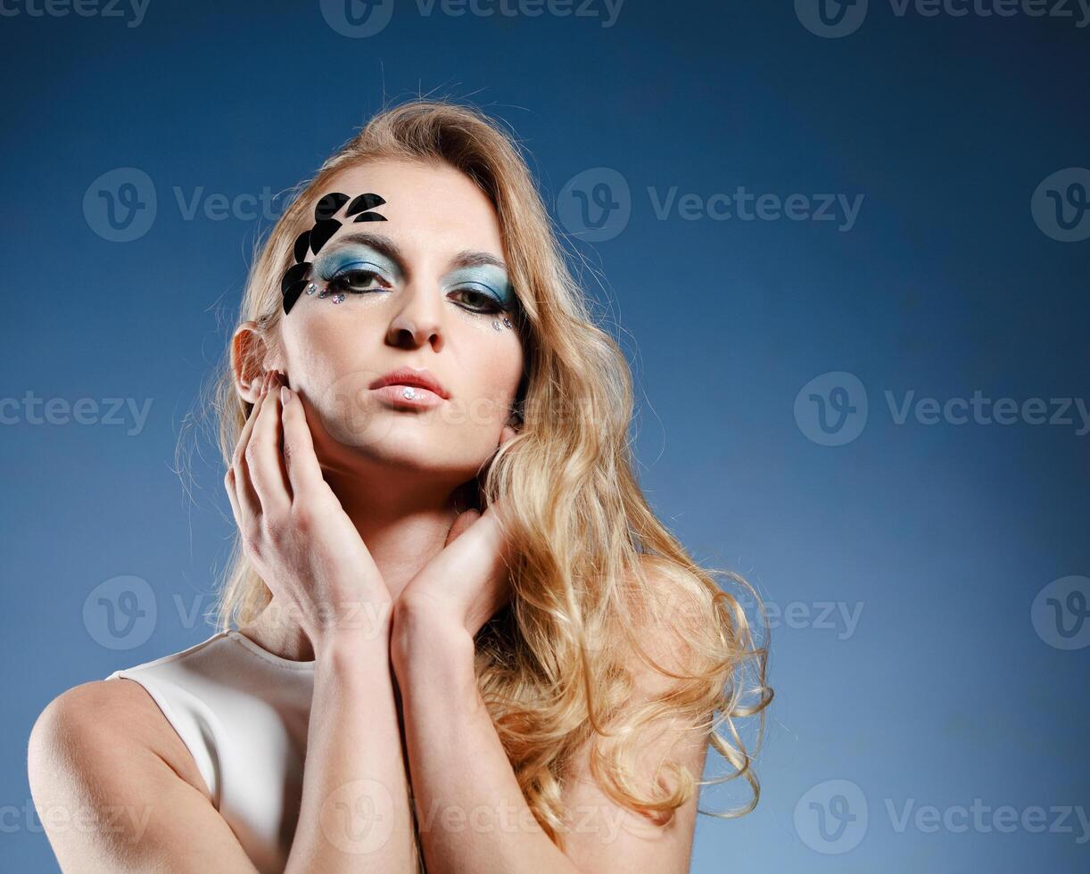 a beautiful blonde woman with blue and black makeup photo