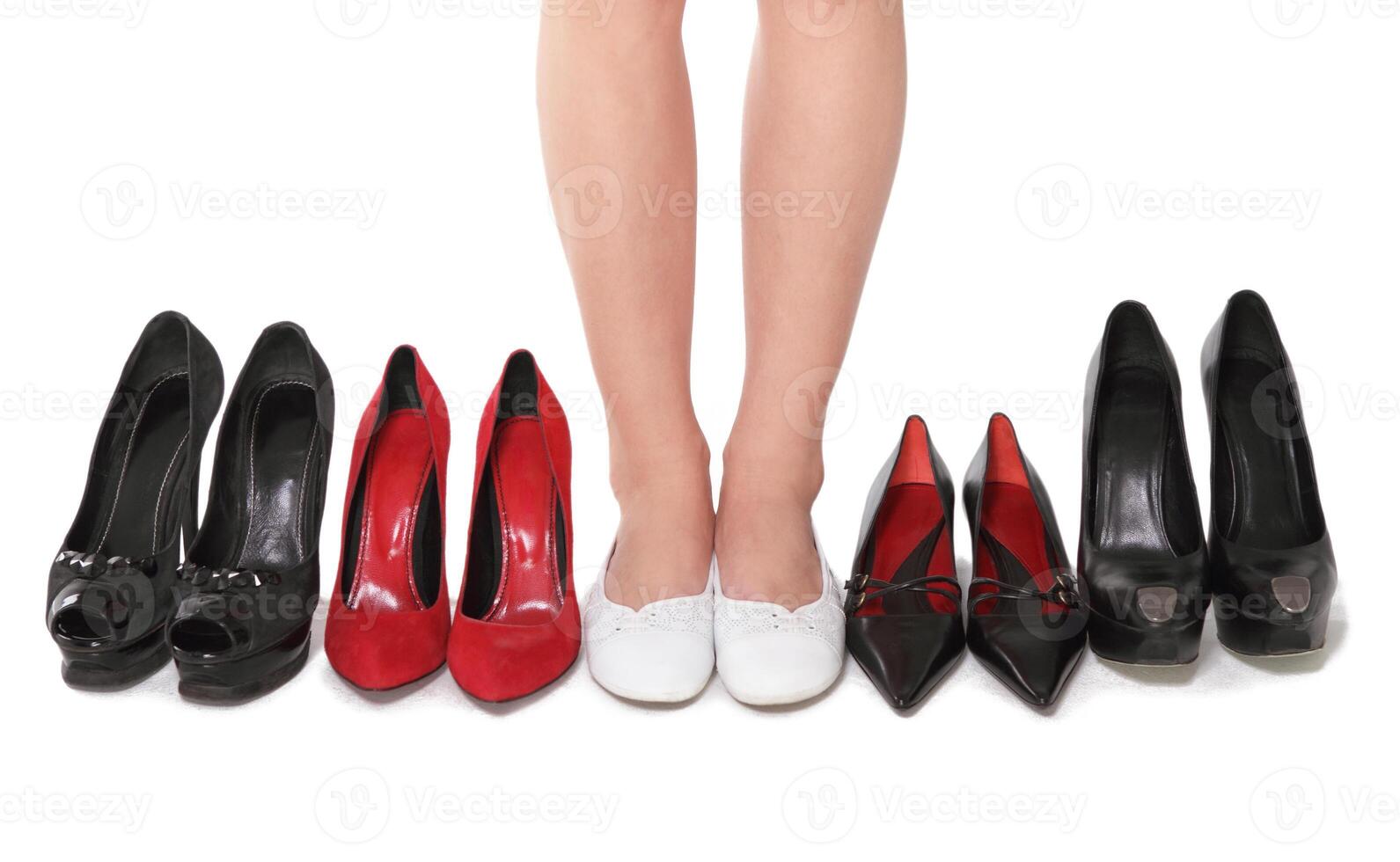 a woman's legs are standing in front of a row of different shoes photo