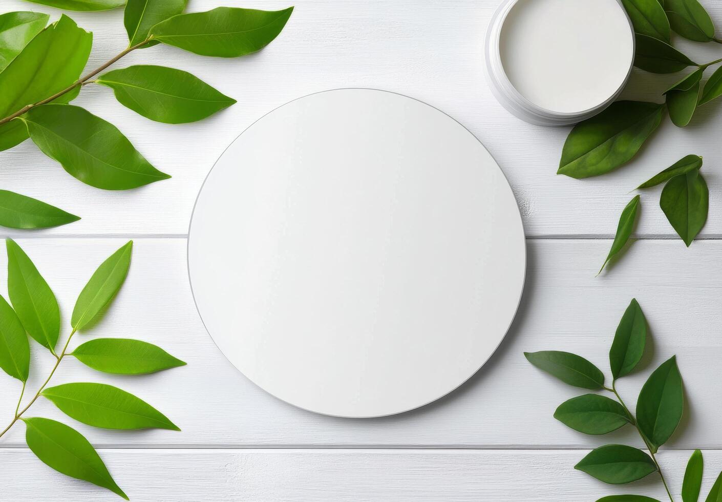 Circular white plate surrounded by vibrant green leaves on a light wooden surface photo