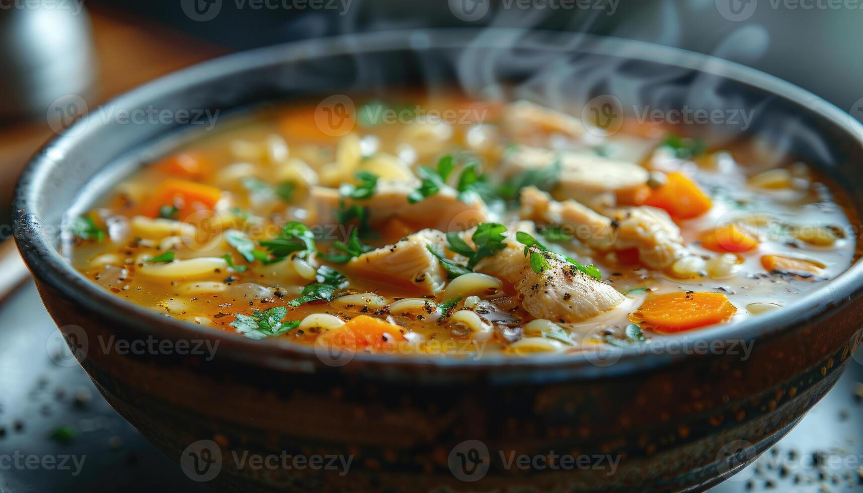 Steaming Bowl of Chicken Noodle Soup with Carrots and Parsley photo