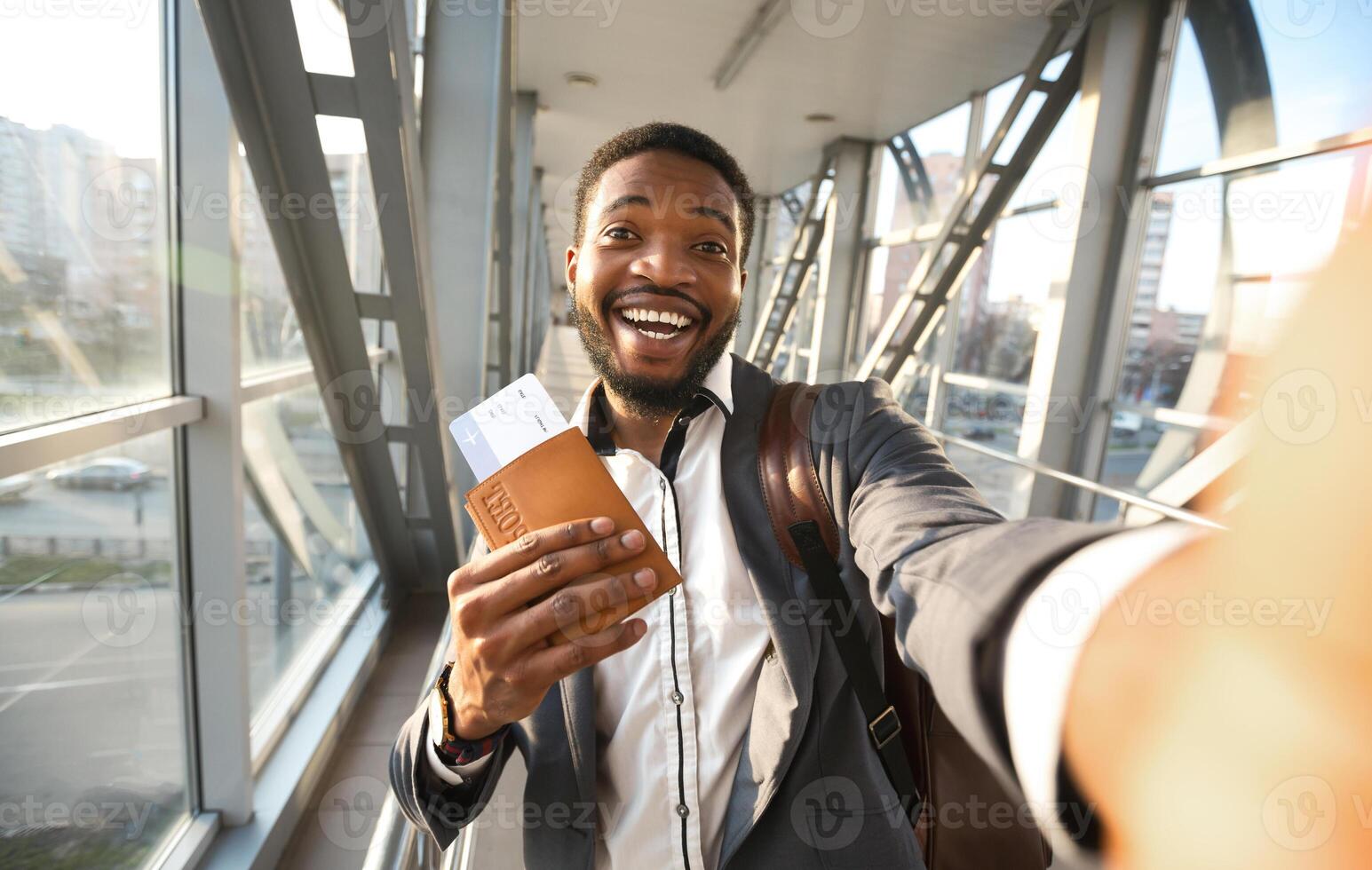 Happy African Businessman Traveler Making Selfie With Passport And Flight Tickets In Airport Indoors. Celebrating End Of Lockdown. Selective Focus photo