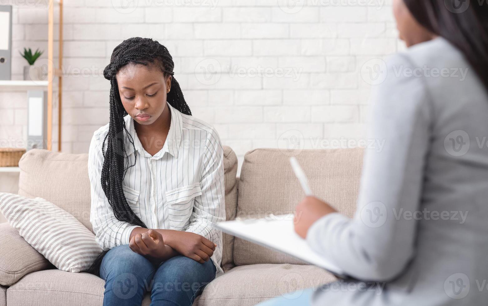 Psychotherapy concept. Upset african american woman sitting on couch at counselor's office photo
