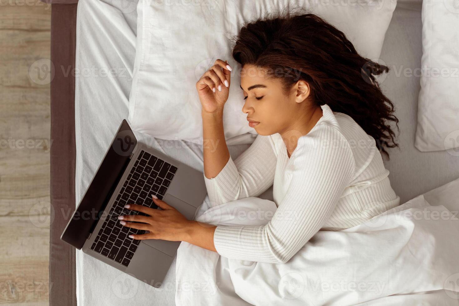 Always In Touch. Top Above High Angle View Of Exhausted Black Freelancer Lady Sleeping In Bed, Holding Hand On Laptop Keyboard, Taking Break At Home. Freelance And Distant Work Concept photo