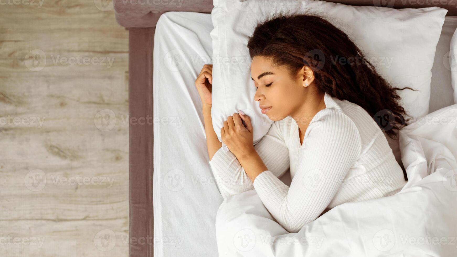 Top above high angle view of calm young black woman sleeping well on the side. African American lady resting, enjoying fresh cotton bedding, soft pillow and comfy mattress, free copy space, banner photo