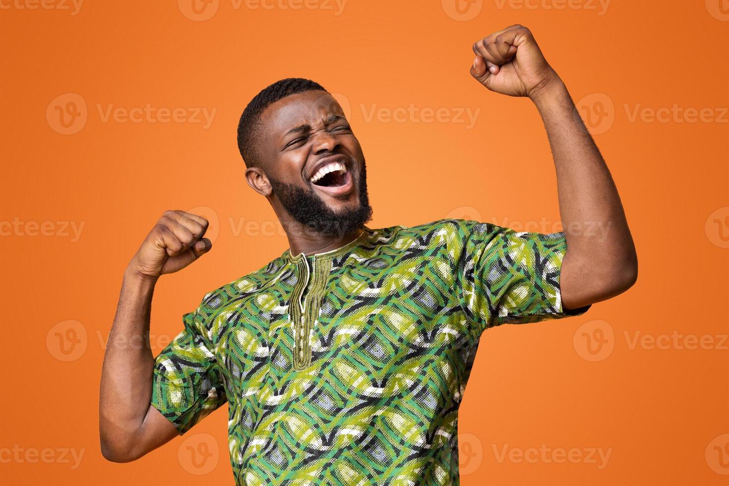 Happy black man winner showing positive emotions over yellow background, won the prize photo