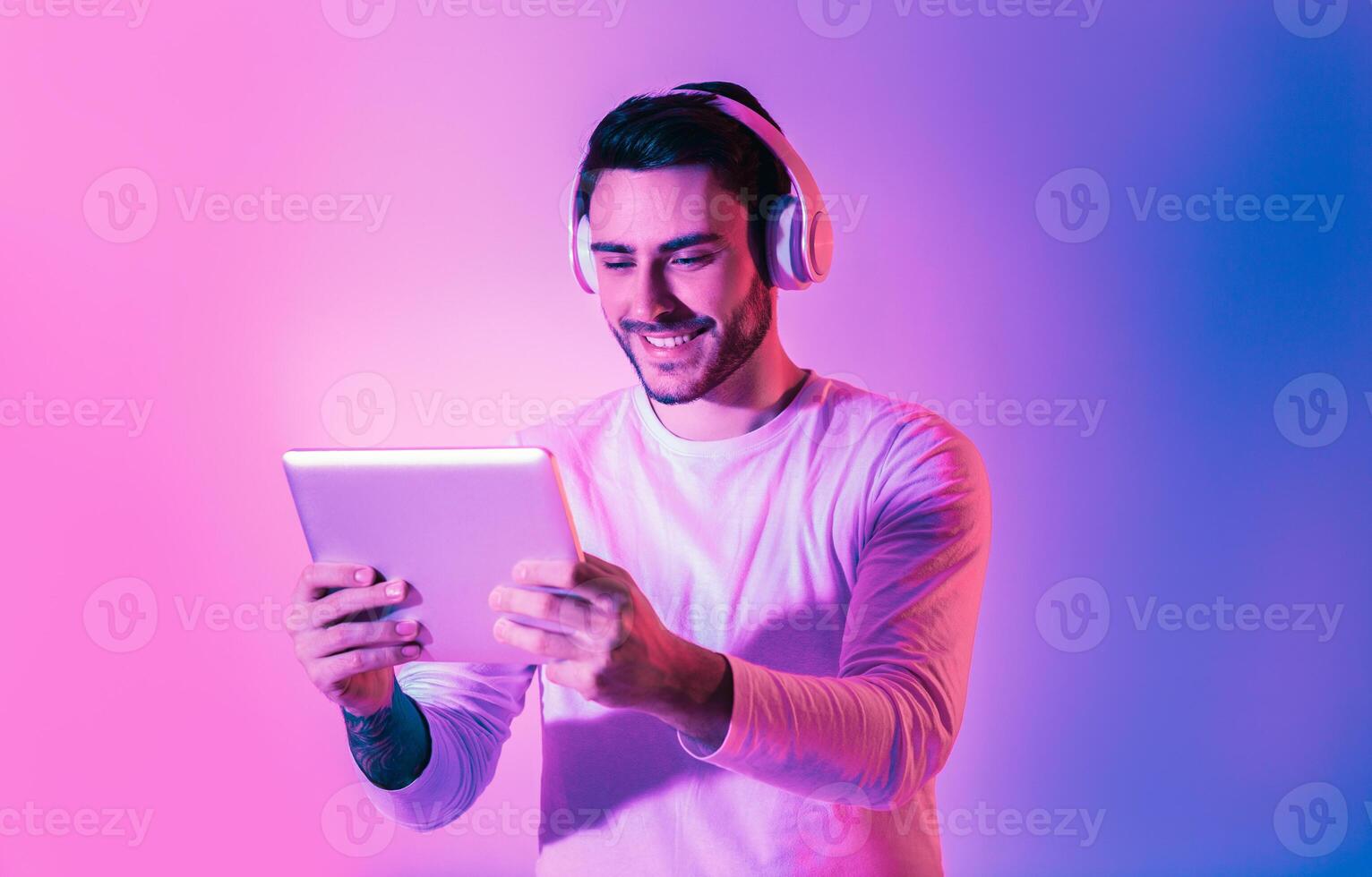 Online game concept. Handsome man with tablet and wireless headphones photo