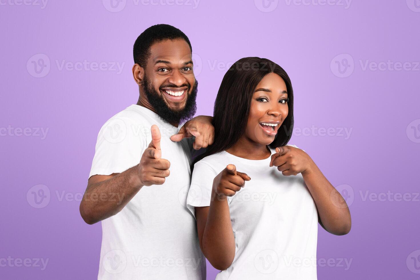 Portrait Of Excited African American Young Couple Pointing Fingers At Camera, Happy Man And Woman Choosing You, Having Fun, Standing Isolated Over Blue Studio Background, Copy Space photo