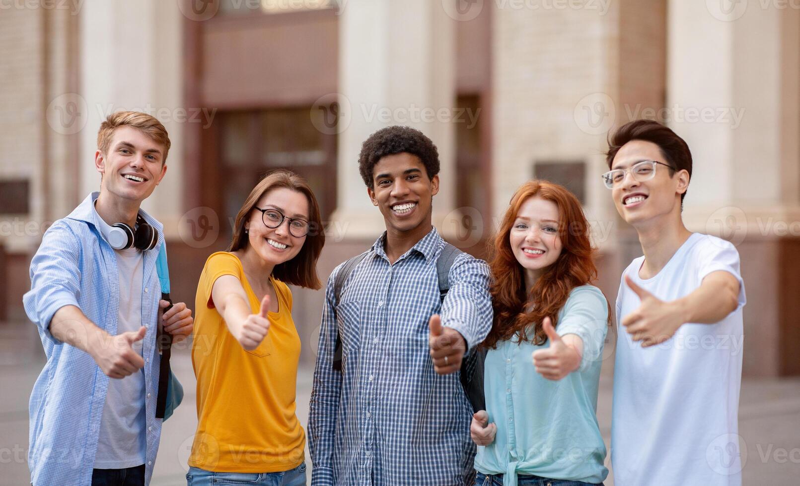 Diverse Students Gesturing Thumbs-Up Smiling To Camera, Approving Their College Educational Program Standing Outside. photo