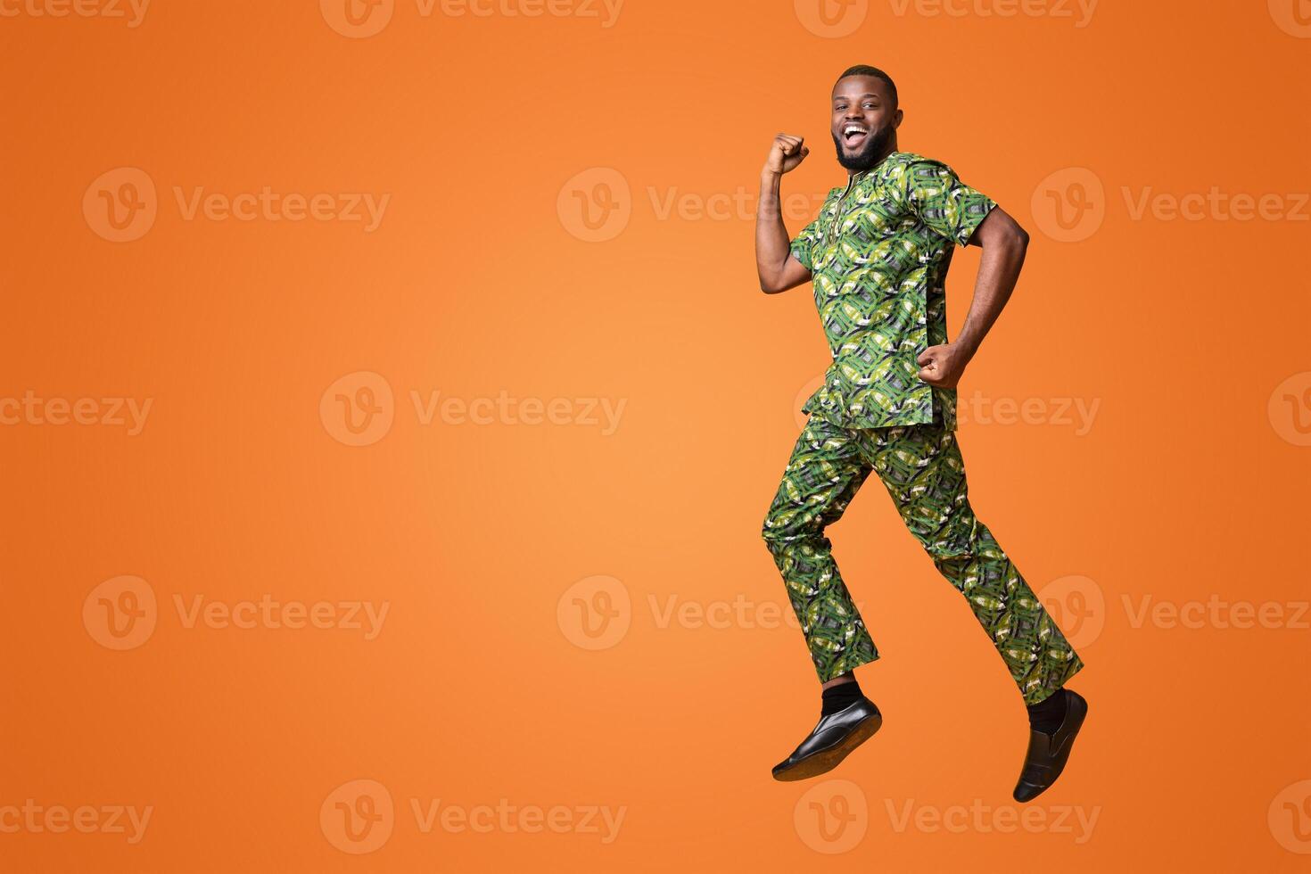 Joyful black man happily jumping up over yellow studio background photo