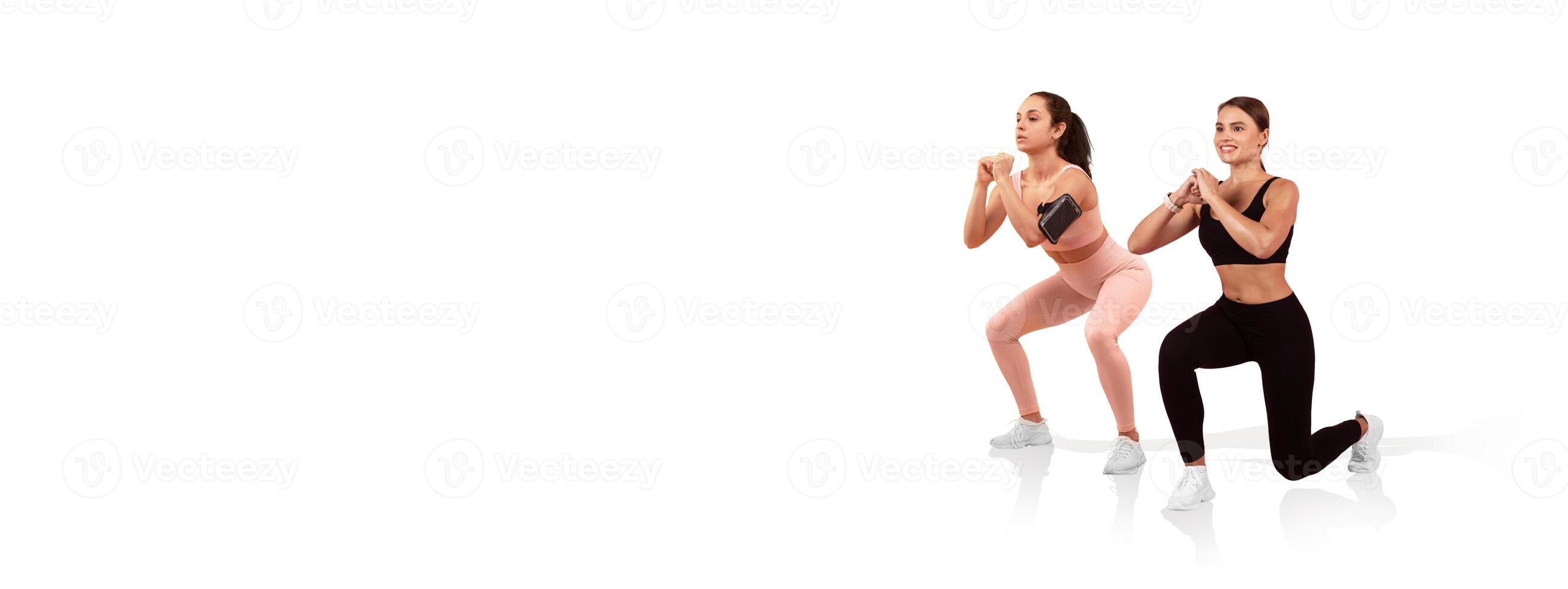 Two women engage in a squat exercise indoors, focusing on their form and technique. They wear matching athletic outfits and show determination as they work out together. photo