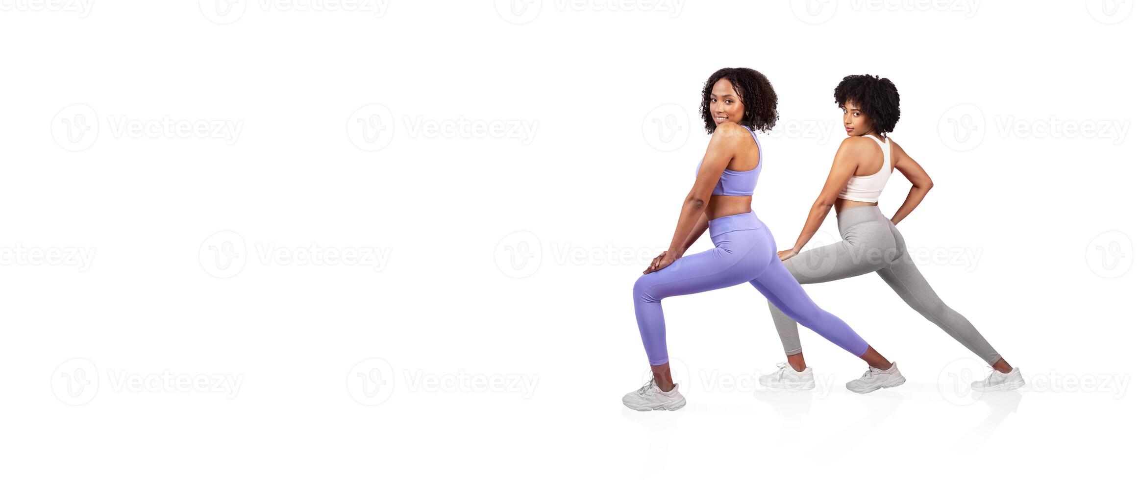 Two women perform athletic poses, highlighting their strength and flexibility. They wear stylish workout attire while positioned against a plain background, emphasizing their focus and determination. photo