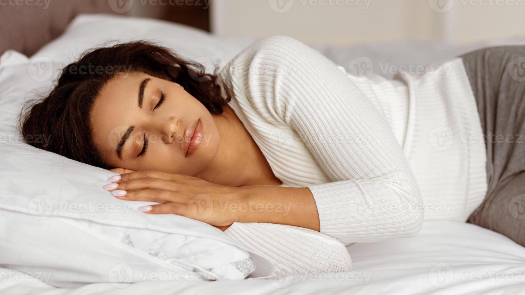 Having Nap. Closeup portrait of calm young black woman sleeping well on the side. Beautiful person resting, enjoying fresh cotton bedding, soft pillow and comfy mattress, banner. Sleep hygiene photo