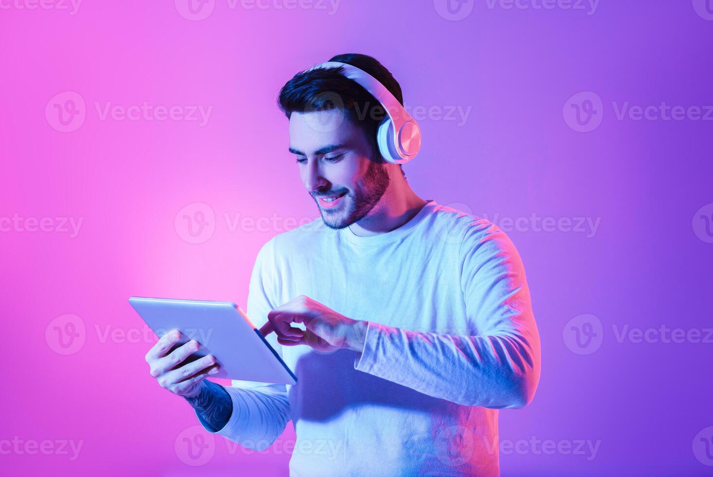 Modern gadgets for joy concept. Happy man in wireless headphones uses tablet photo