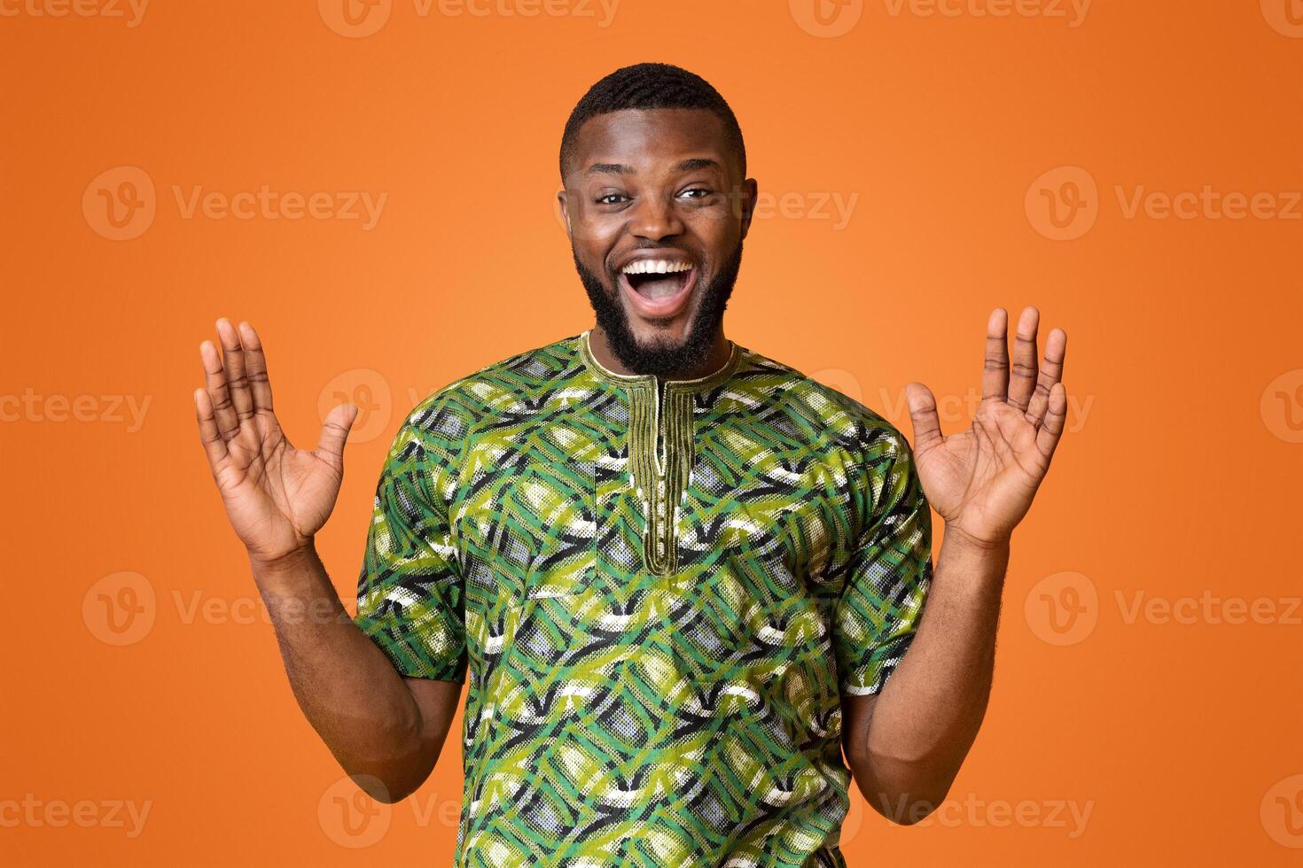 Surprised african man with hands up looking at camera over yellow studio background photo