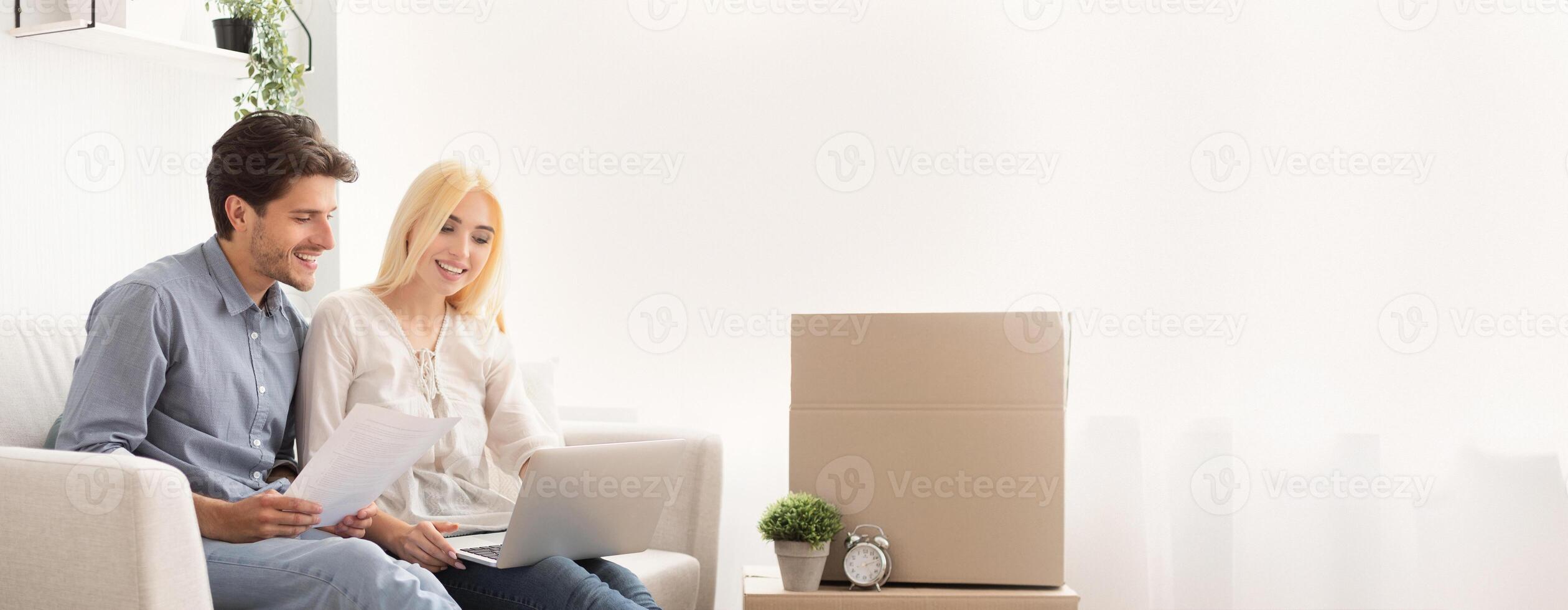 Husband And Wife Using Laptop Looking Design Project Sitting On Couch In Own House. Moving Into New Home. Copy Space photo