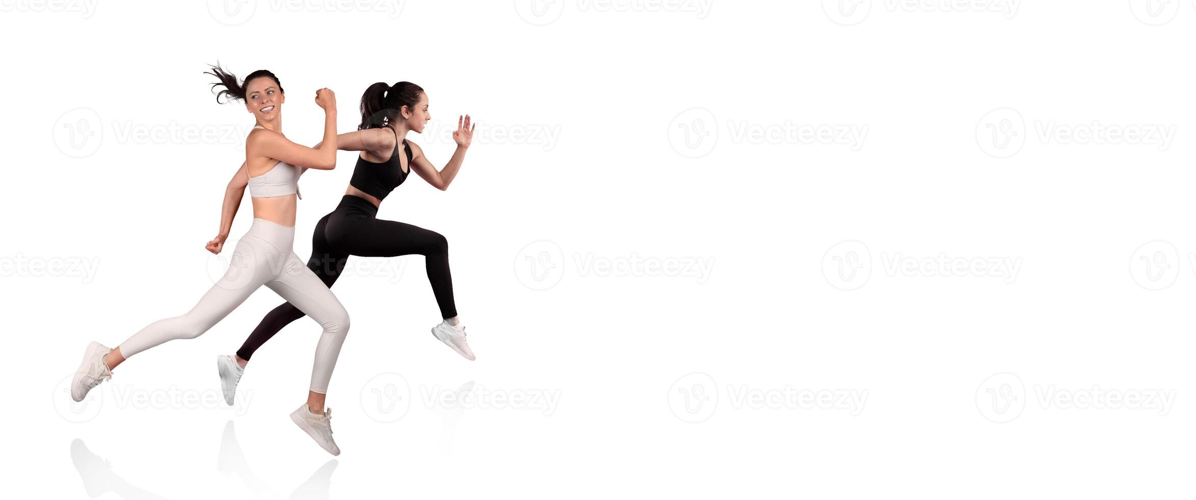 Two women in sporty outfits are sprinting energetically against a plain backdrop. Their dynamic movements showcase fitness and determination, highlighting athleticism and teamwork. photo