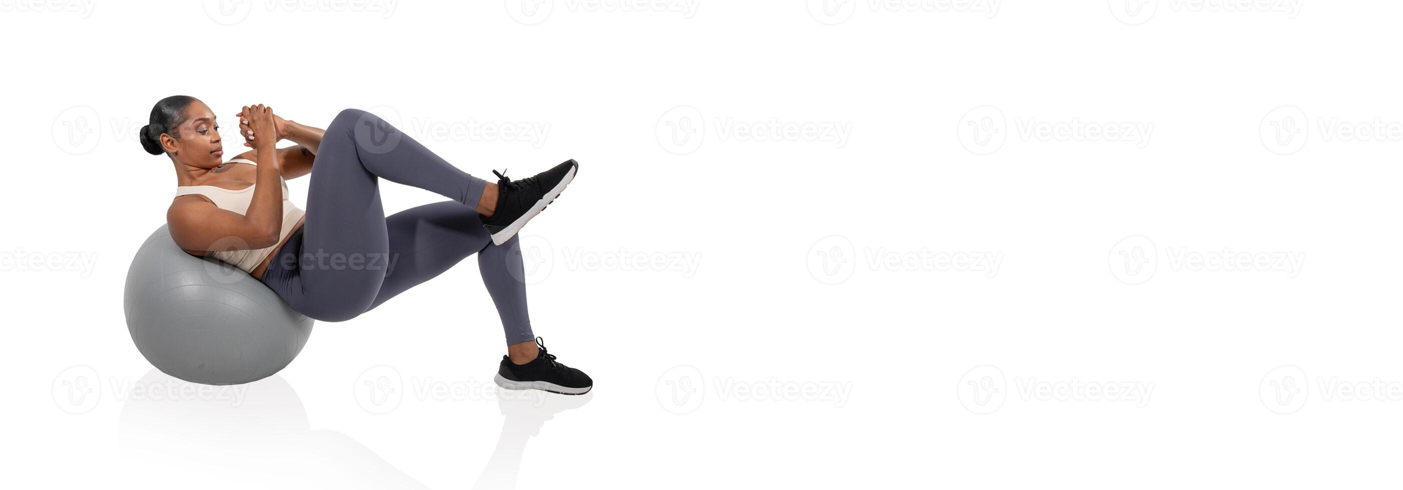 A woman engages in core strengthening by performing bicycle crunches on a stability ball. She is focused and positioned in a well-lit gym setting that promotes fitness. photo