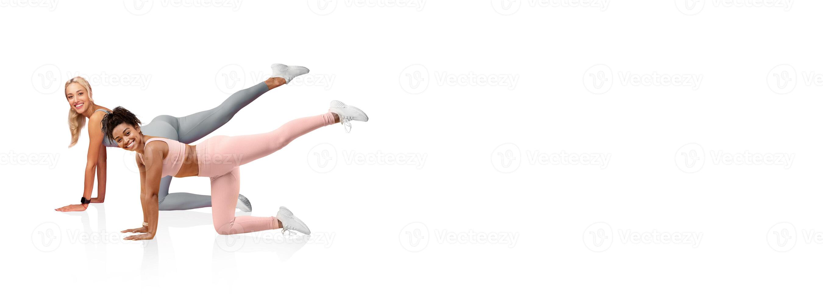 Two women are engaged in a fitness routine, showcasing leg lifts. They are in a bright, airy room, dressed in functional workout attire, focused on their exercise method. photo