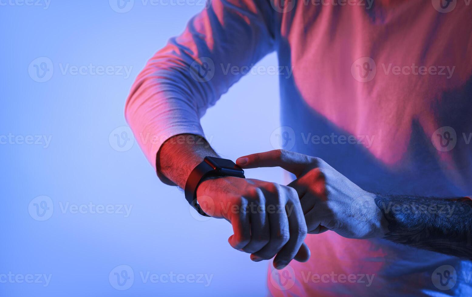 Millennial man in neon with smartwatch on hand, cropped photo