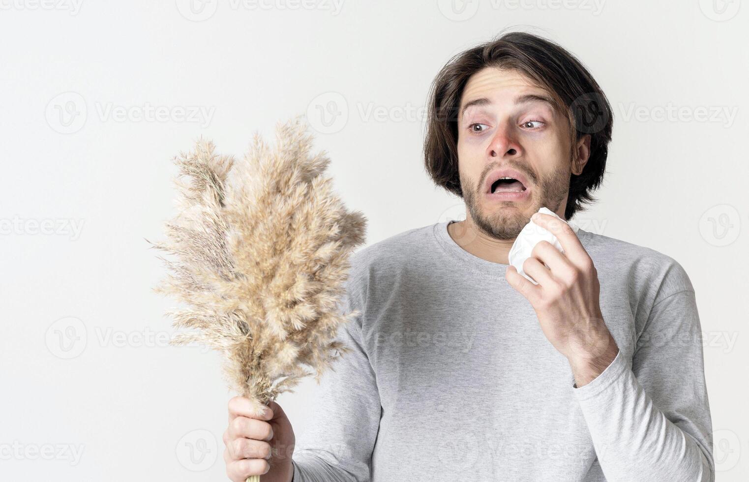 Shocked man holds grass and sneezes in napkin in hand photo