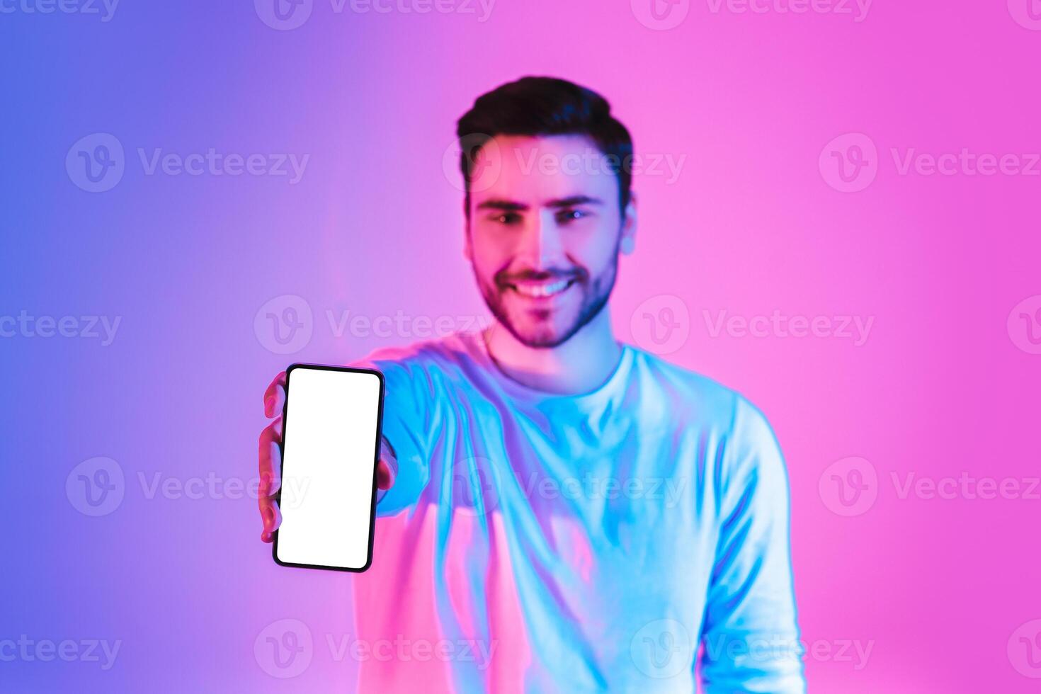 Online victory. Young man shows smartphone with blank screen photo