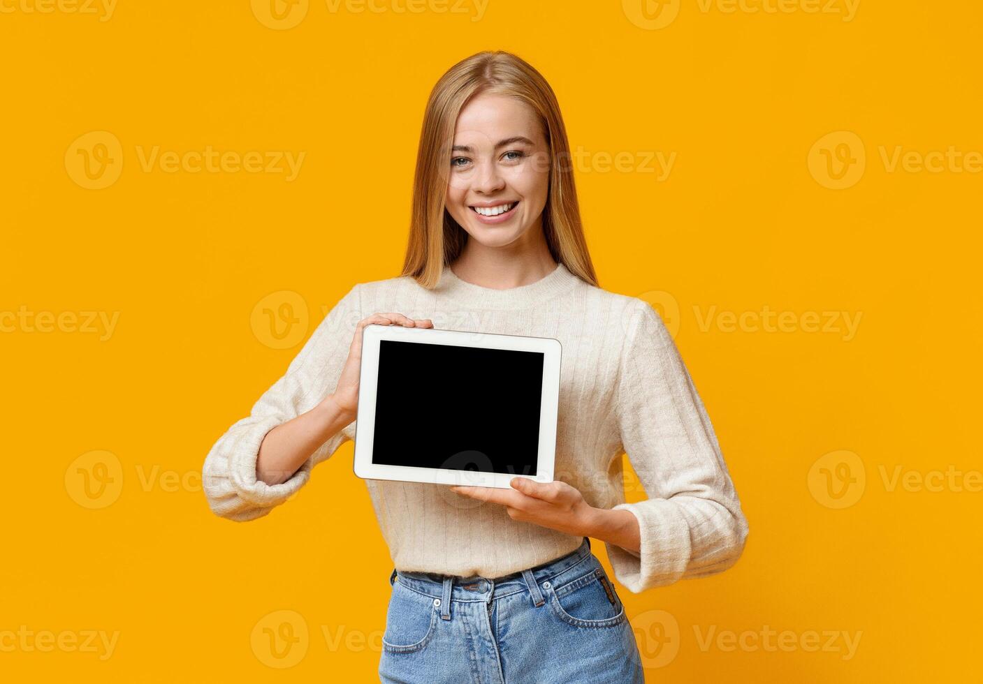 Digital tablet with black blank screen in young girl's hands, orange backgroung with free space photo