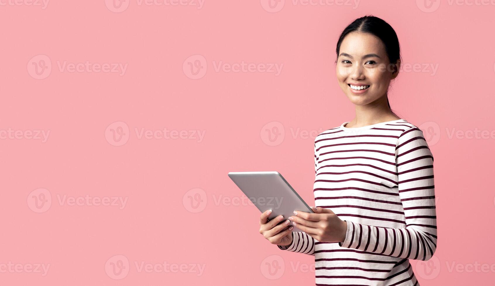 Modern Technologies For Leisure. Portrait Of Young Asian Female Using Digital Tablet And Smiling At Camera, Happy Korean Woman With Modern Device In Hands Posing Over Pink Background, Copy Space photo